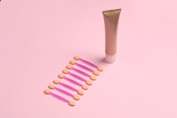 Set of applicators for makeup and foundation tube on a pink background