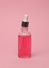 Serum bottle with pipette on a pink background. Beauty concept