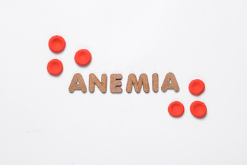 Red blood cells model and word anemia on white background. Medicine and healthcare