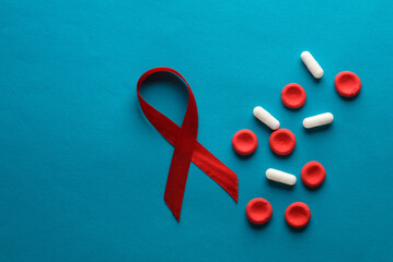 Red blood cells model with pills, aids awareness ribbon on blue background
