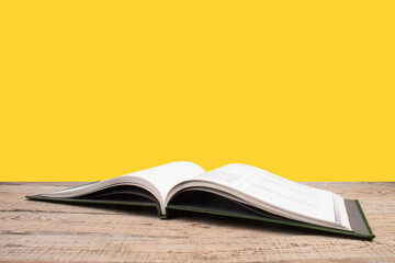 open book. Composition with hardback books, fanned pages on wooden deck table and yellow background. Books stacking. Back to school. Copy Space. Education background.