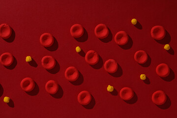 Red blood cells with lipids model made from plasticine on red background. Cholesterol