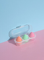Obraz na płótnie Canvas Makeup sponge blenders in pack on a pink blue background with shadow. Beauty concept. Creative layout, minimalism