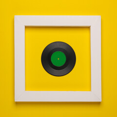 Obraz premium Vinyl record in white frame on yellow background. Creative layout. Minimalism