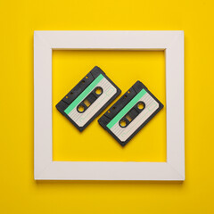 Obraz premium Retro Audio cassettes in white frame on yellow background. Creative layout. Minimalism