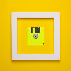 Retro floppy disk in white frame on yellow background. Creative layout. Minimalism