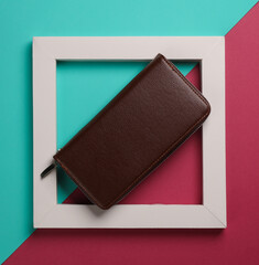 Brown leather wallet in white frame on pink blue background. Creative fashion layout. Minimalism