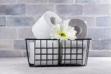 Basket with rolls of toilet paper and white flower on stone background. International toilet paper...