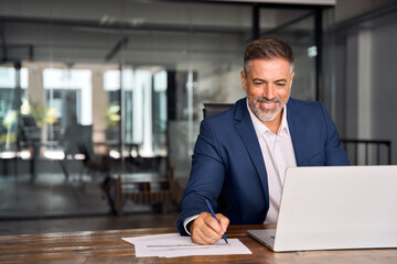 Middle-age Hispanic man using laptop computer for business studying, watch online financial webinar...