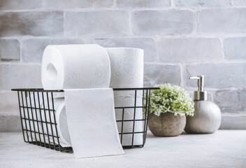 Basket with rolls of toilet paper and white flower on stone background. International toilet paper...