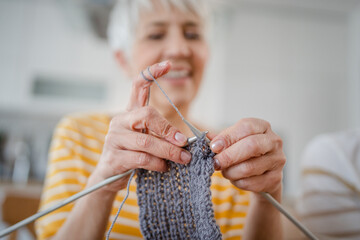 close up on hands of senior caucasian woman needle work knitting