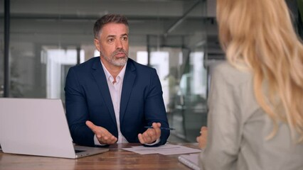 Lawyer or real estate agent make consultation for client. Mature Latin business man and European business woman discussing project on laptop sitting at table in office. Business people work together. - Powered by Adobe