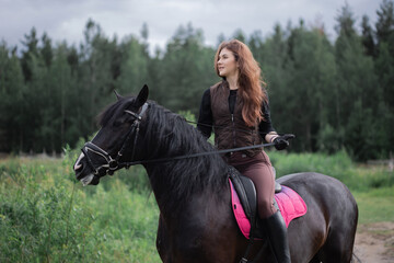 Obraz premium Equestrian sports. A young woman in the saddle, a rider and her horse outdoors, riding in the woods.
