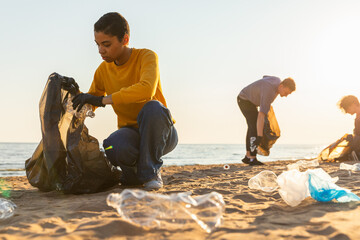 Earth day. Volunteers activists collects garbage cleaning of beach coastal zone. Woman and mans puts plastic trash in garbage bag on ocean shore. Environmental conservation coastal zone cleaning - obrazy, fototapety, plakaty