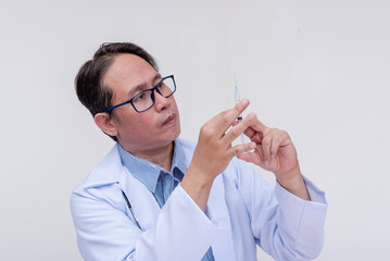 A doctor checks the dosage of his syringe. Of asian descent, middle aged male. Isolated on a white background.
