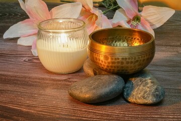 Hand-crafted Tibetan bell on a wooden surface, surrounded by river rocks and a flickering candle