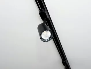 Deurstickers Background Led track lamp on the ceiling in the interior. Interior spotlight in black color. Modern track lamp with a lot of swivel lamps. The concept of lighting in the house. © Andrii
