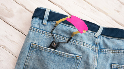 Slingshot in pants pocket. The object is a slingshot with a pink rubber band.