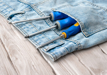 Screwdrivers with a blue handle, Phillips and a different set in the pocket of jeans pants. The...
