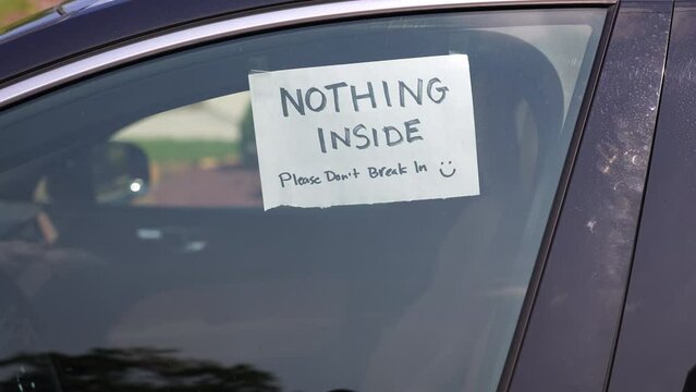 A car owner places a hand-written sign on the door window saying that no valuables are inside and to please not break in.	