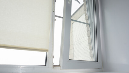 The double-glazed window is white with roller blinds. The window is not opened correctly. window repair, breakage.