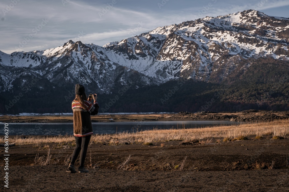 Wall mural Young woman photographing the snowy mountain in the highland