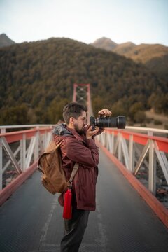 Professional photographer taking photos with his digital camera on a bridge