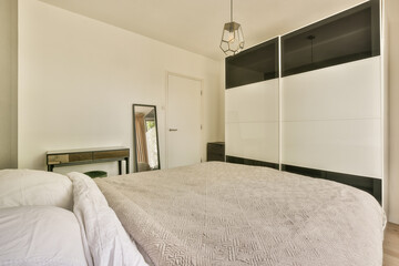 a bedroom with a bed, dresser and mirror on the wall in front of the bed is black and white