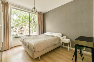 a bedroom with a bed, desk and window looking out onto the street in front of the apartment's...