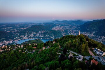 Stunning aerial view of a lighthouse sitting on a mountaintop overlooking Lake Como.