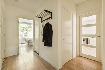 the inside of a house with wood floors and white walls, there is a coat rack hanging on the wall
