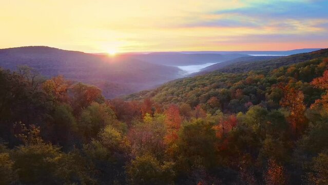 Beautiful mountain view sunrise over Ozark Mountains with foggy valley and autumn colored trees shot via drone aerial
