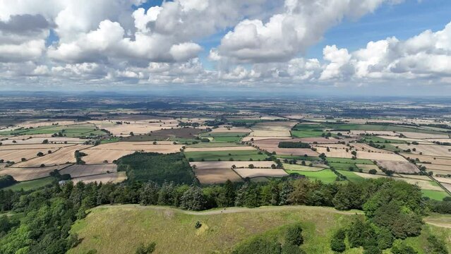 4K rising drone establishing shot revealing a green rural countryside landscape behing a large hill mountain hiking spot on a sunny day in rural england