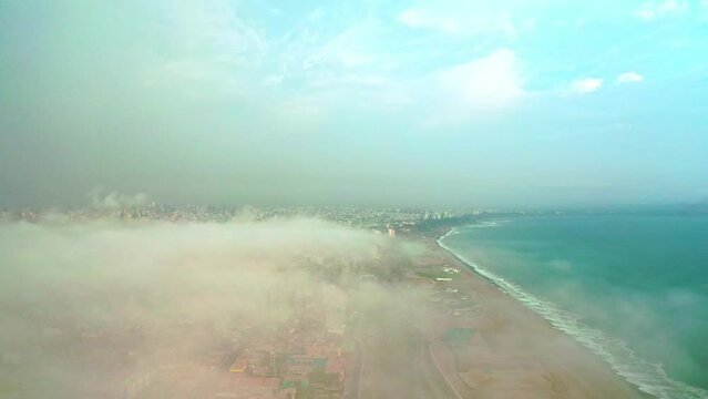 Aerial view of Lima between the clouds, view flying over the tops of the clouds and unveiling the city.
