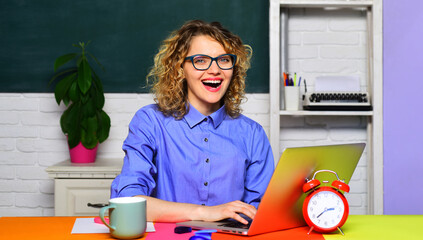 Smiling university student girl preparing for test or exam using laptop. High school. Female teacher in glasses working with notebook computer in classroom. Teacher job. Education, learning, teaching.