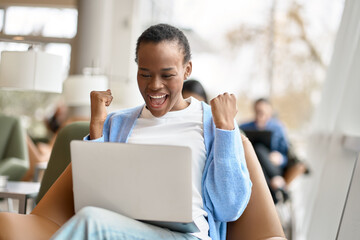 Happy excited African Black girl college student celebrating reading admission email looking at...