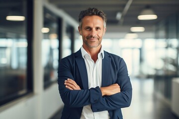 Businessman standing in office. Confident Happy middle aged businessman with arms crossed pose. Good-looking middle-aged businessman