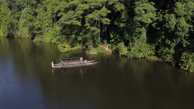 drone traveling, zooming out from a boat full of tourists docking on the border of a lake in the Peruvian rainforest