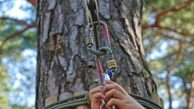 Caucasian Child Girl Attaching Double Spring Loaded Carabiner Snap Hook to Metal Safety Cable Line in Rope Park Obstacle Course