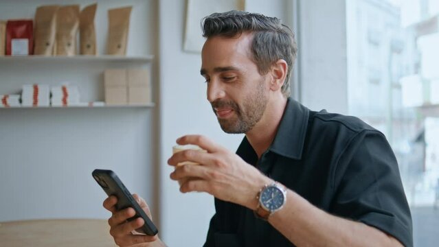 Handsome guy chatting cellphone social networks drinking coffee in cafe close up