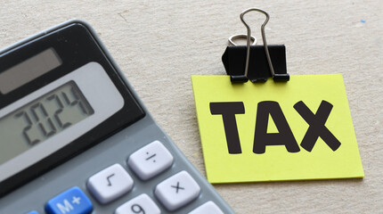 The word TAX on a small piece of paper.. Tax Business Concept .