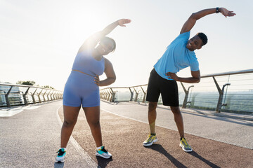 Obraz premium Positive african american man and woman working out on street, doing exercises in park