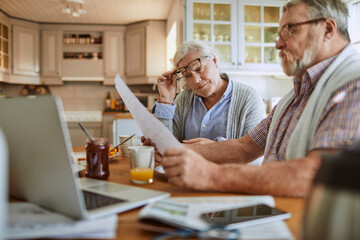Senior couple going over their bills and home finances while having breakfast in the morning