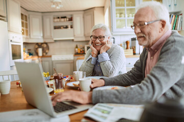 Senior caucasian coule having breakfast together and using a laptop