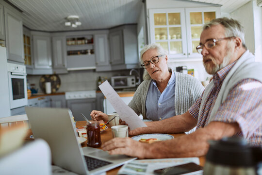 Senior couple going over their bills and home finances while having breakfast in the morning