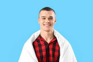 Young man with blanket on blue background