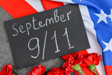 Fototapeta na wymiar Card with date of National Day of Prayer and Remembrance for the Victims of the Terrorist Attacks, carnation flowers, USA flag on grunge grey background