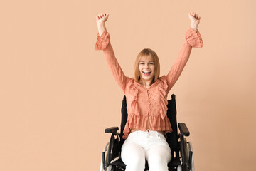 Happy young woman in wheelchair on beige background