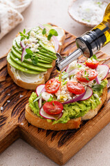 Avocado toasts with radishes, tomatoes and feta topped with olive oil