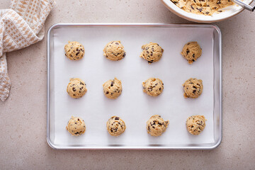 Chocolate chip cookie dough scoopes on a cookie sheet ready to be baked - Powered by Adobe